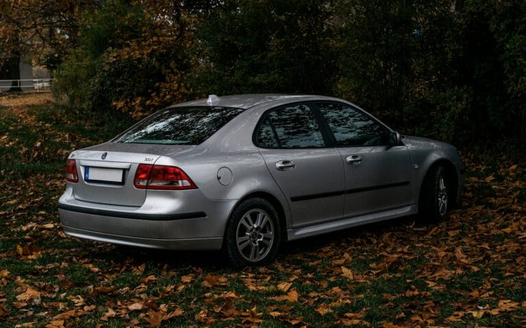 a silver car parked in front of some trees