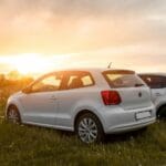 white sedan on green grass field during sunset