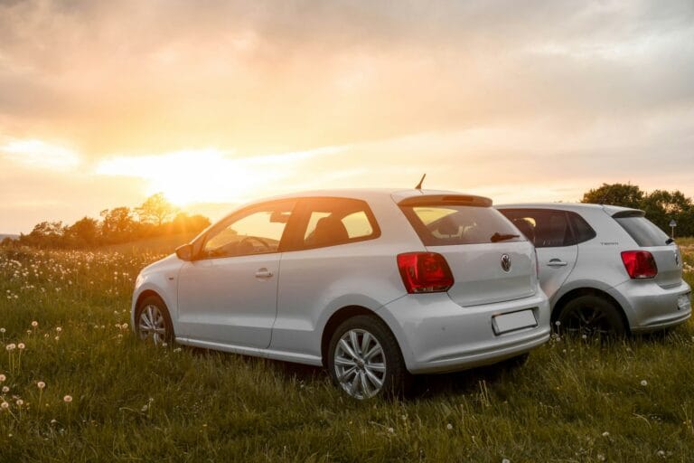 white sedan on green grass field during sunset